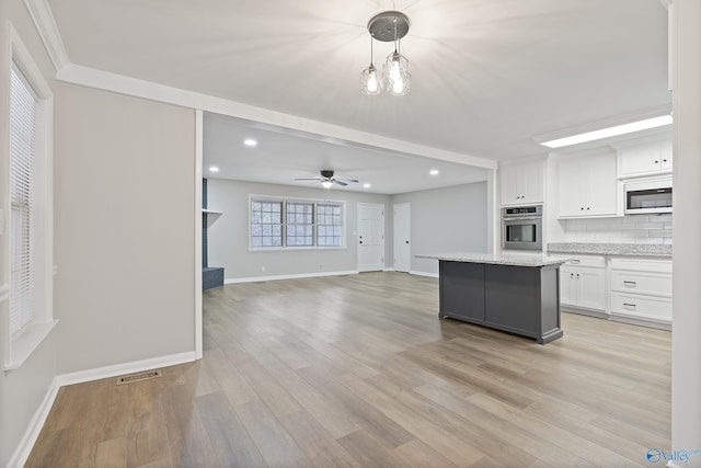 kitchen featuring oven, visible vents, tasteful backsplash, white cabinetry, and white microwave