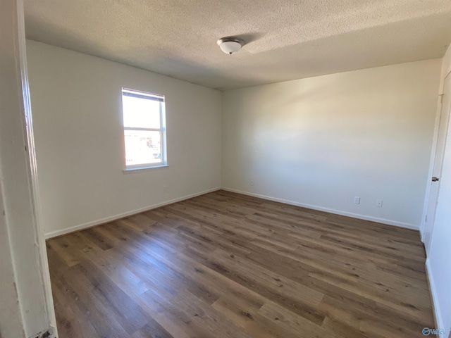 spare room with a textured ceiling and dark hardwood / wood-style flooring