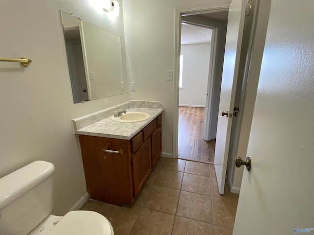 bathroom with a textured ceiling, toilet, tile patterned floors, and vanity
