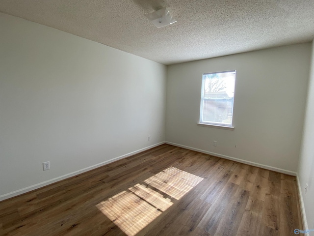 empty room with hardwood / wood-style flooring and a textured ceiling