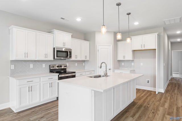 kitchen featuring stainless steel appliances, white cabinets, visible vents, and a sink