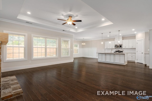 unfurnished living room with ceiling fan, crown molding, dark hardwood / wood-style floors, and a raised ceiling