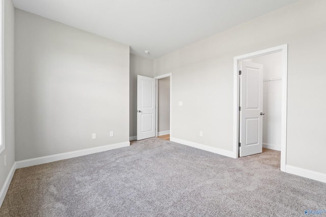 unfurnished bedroom featuring a spacious closet and light colored carpet