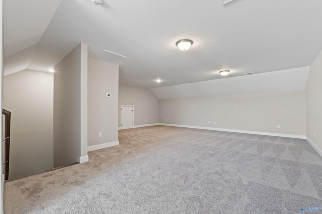 additional living space with light colored carpet and vaulted ceiling