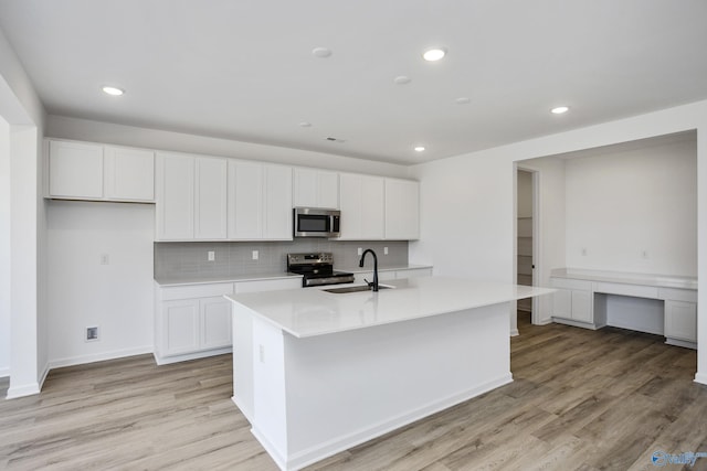 kitchen featuring white cabinets, appliances with stainless steel finishes, a center island with sink, and sink