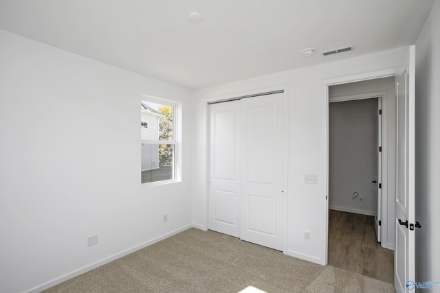 unfurnished bedroom with light carpet and a closet