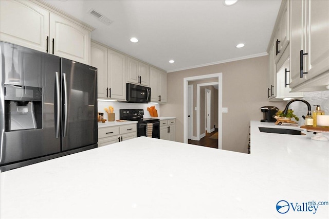 kitchen featuring black appliances, tasteful backsplash, crown molding, white cabinetry, and sink