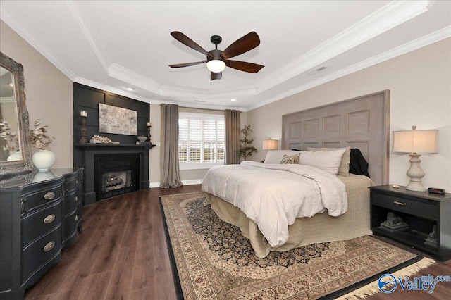 bedroom featuring dark hardwood / wood-style flooring, ceiling fan, a tray ceiling, and crown molding