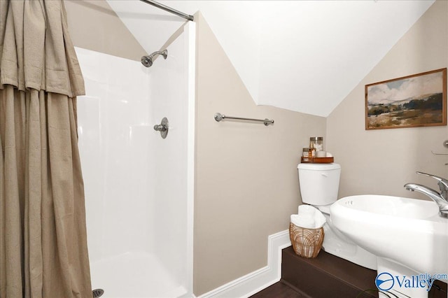 bathroom with lofted ceiling, toilet, a shower with shower curtain, and sink