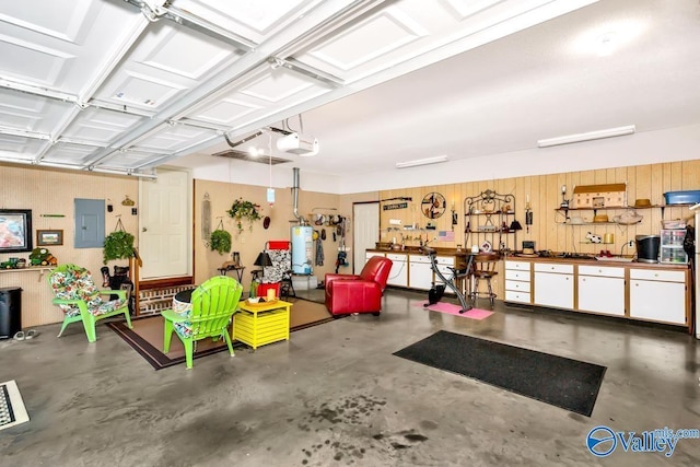 garage featuring wood walls, a garage door opener, water heater, and electric panel