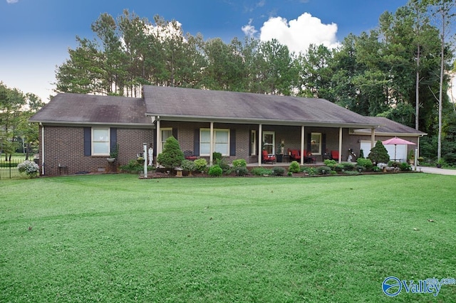 view of front of house featuring a porch, brick siding, an attached garage, and a front lawn