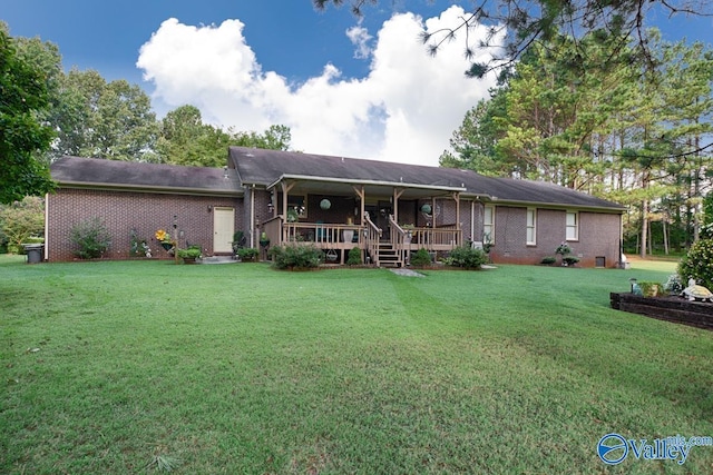 back of property with a yard, a deck, and brick siding