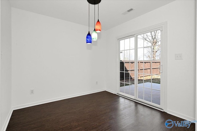 empty room with dark wood-type flooring, visible vents, and baseboards