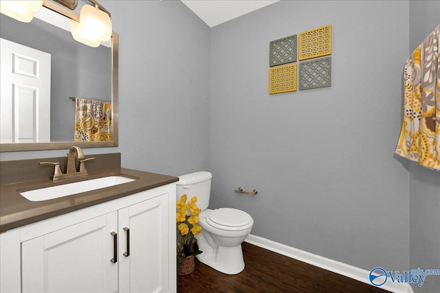 bathroom with baseboards, vanity, toilet, and wood finished floors