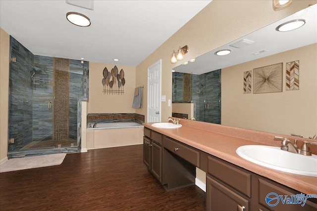 bathroom with wood finished floors, a sink, a bath, double vanity, and a stall shower