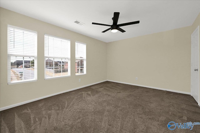 spare room with carpet floors, a ceiling fan, visible vents, and baseboards