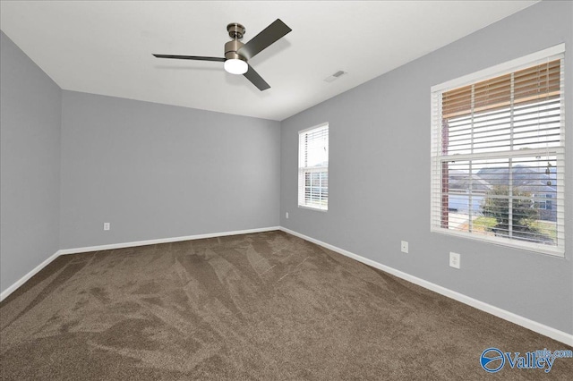 unfurnished room featuring ceiling fan, dark colored carpet, visible vents, and baseboards