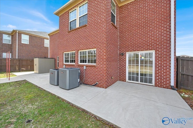 back of property featuring brick siding, a patio area, fence, and central air condition unit