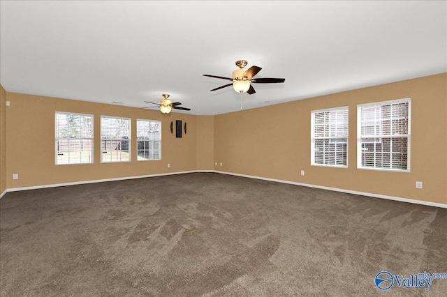 empty room featuring dark colored carpet, ceiling fan, and baseboards