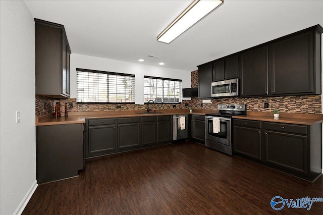 kitchen with dark wood-style floors, tasteful backsplash, appliances with stainless steel finishes, and a sink