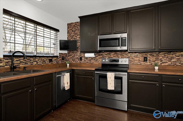 kitchen featuring dark wood-style flooring, appliances with stainless steel finishes, backsplash, and a sink