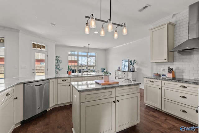 kitchen with dark wood finished floors, visible vents, stainless steel dishwasher, a sink, and wall chimney exhaust hood