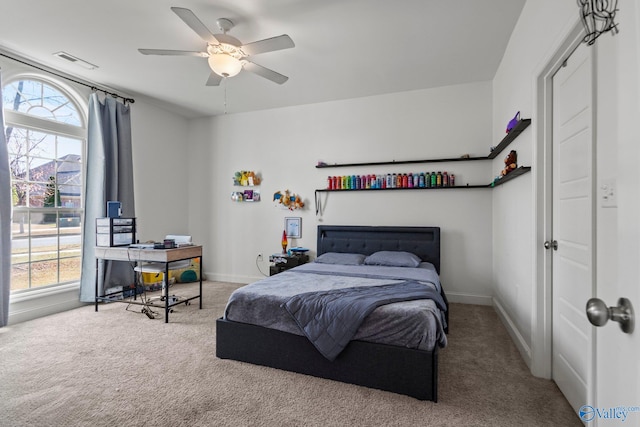 carpeted bedroom with visible vents, baseboards, and ceiling fan
