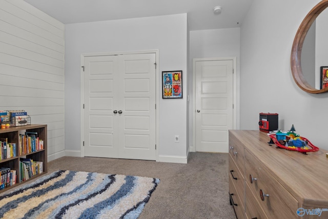 bedroom with wooden walls, carpet, a closet, and baseboards