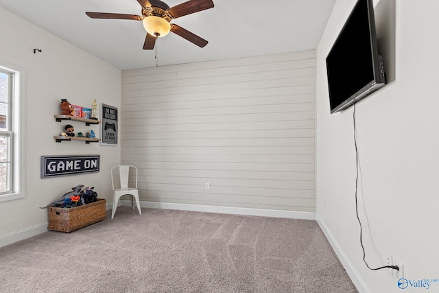 interior space featuring ceiling fan, carpet flooring, baseboards, and wood walls