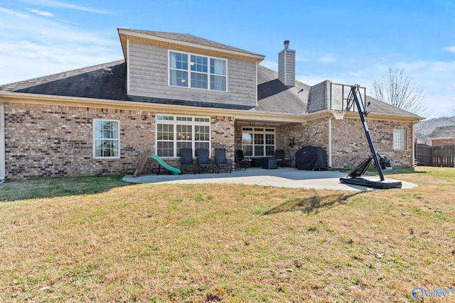 back of property featuring brick siding, a yard, a patio area, and a chimney