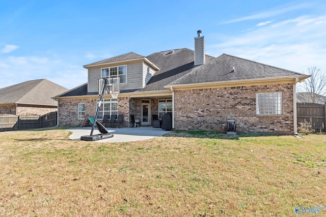 back of house featuring a fenced backyard, a chimney, brick siding, a patio area, and a yard