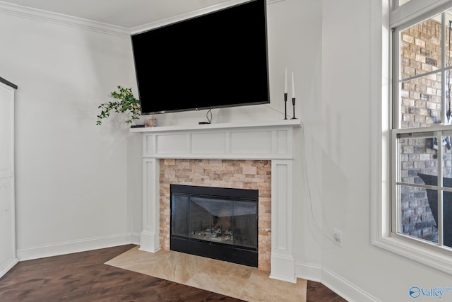 interior details with a fireplace with flush hearth, wood finished floors, baseboards, and crown molding