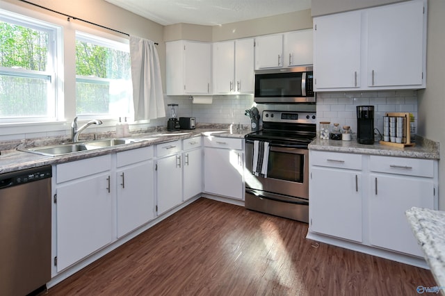 kitchen featuring a sink, white cabinetry, appliances with stainless steel finishes, decorative backsplash, and dark wood-style floors