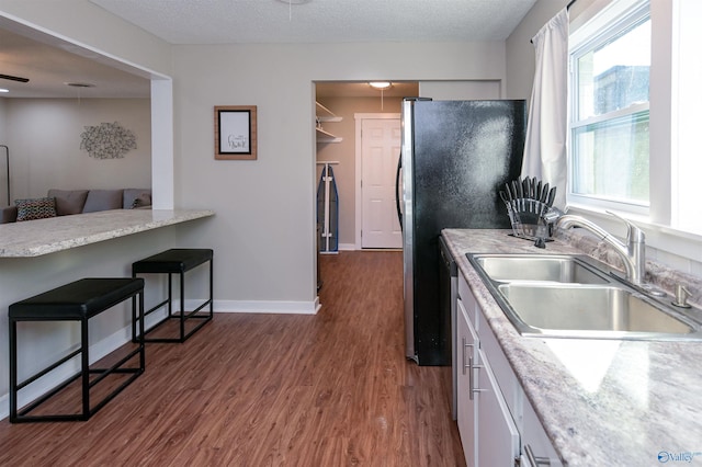 kitchen featuring a breakfast bar, a textured ceiling, dark wood finished floors, and a sink