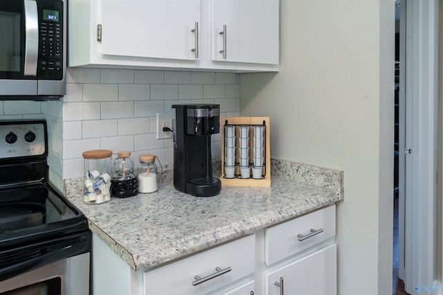 kitchen featuring appliances with stainless steel finishes, backsplash, and white cabinets