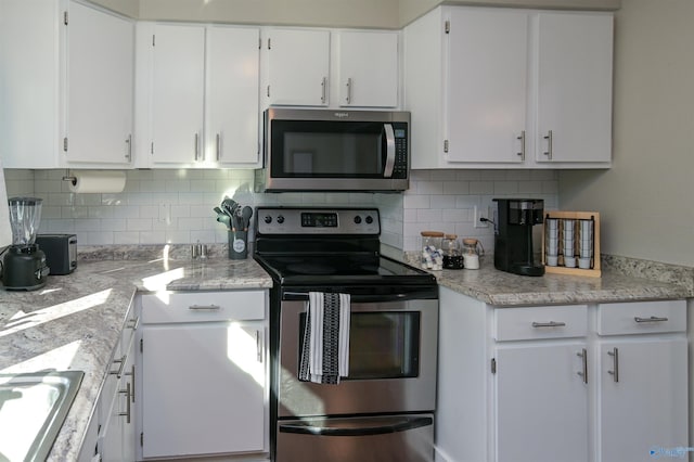 kitchen with tasteful backsplash, white cabinetry, appliances with stainless steel finishes, and light countertops