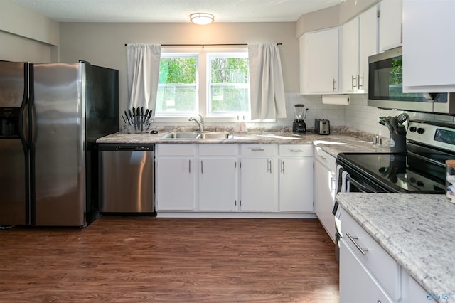 kitchen with dark wood-style floors, decorative backsplash, appliances with stainless steel finishes, white cabinetry, and a sink