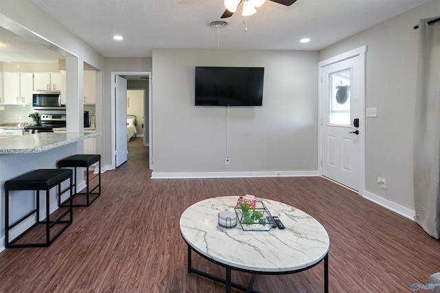 living room with dark wood finished floors, visible vents, a ceiling fan, a textured ceiling, and baseboards