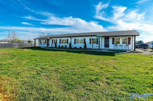 ranch-style home featuring a front lawn and fence