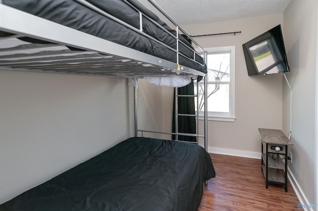 unfurnished bedroom featuring a textured ceiling, baseboards, and wood finished floors