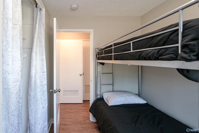 bedroom featuring a textured ceiling and wood finished floors