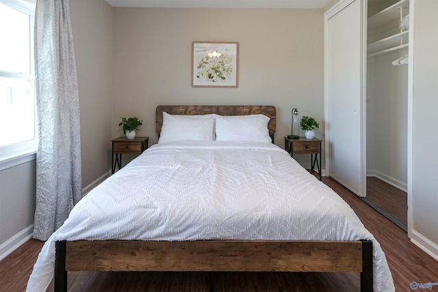 bedroom with dark wood-style floors, a closet, and baseboards