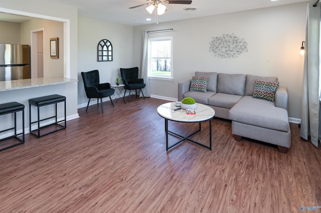 living room with visible vents, ceiling fan, baseboards, and wood finished floors