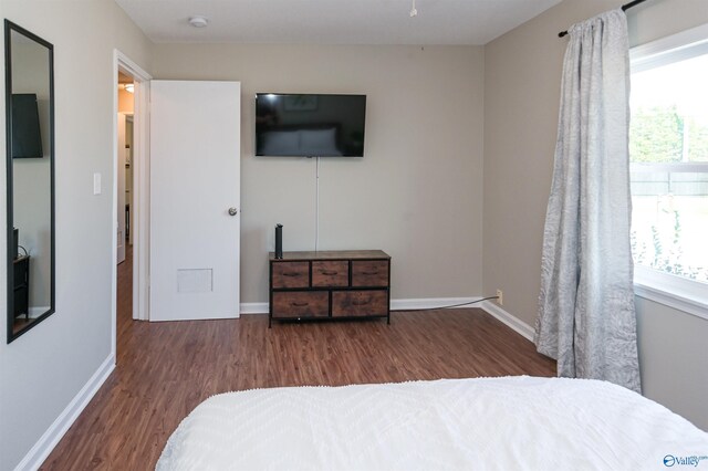 bedroom with multiple windows, baseboards, and wood finished floors