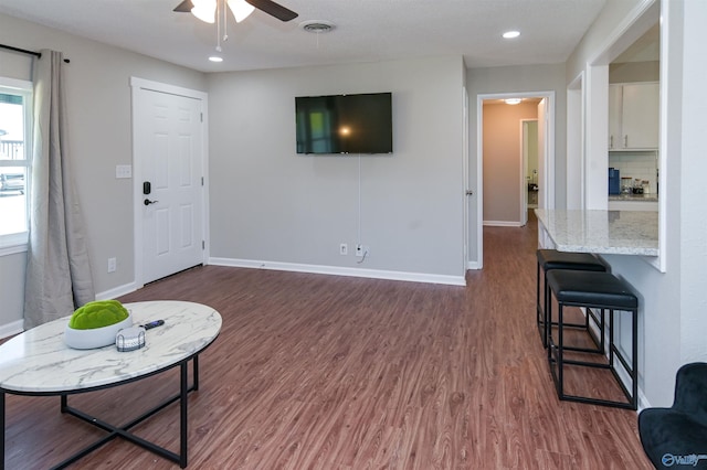 living room with visible vents, baseboards, dark wood finished floors, and a ceiling fan