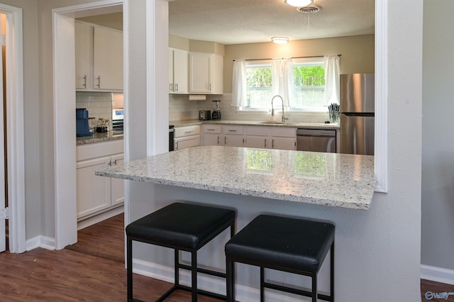 kitchen featuring stainless steel appliances, a breakfast bar, a sink, and white cabinetry