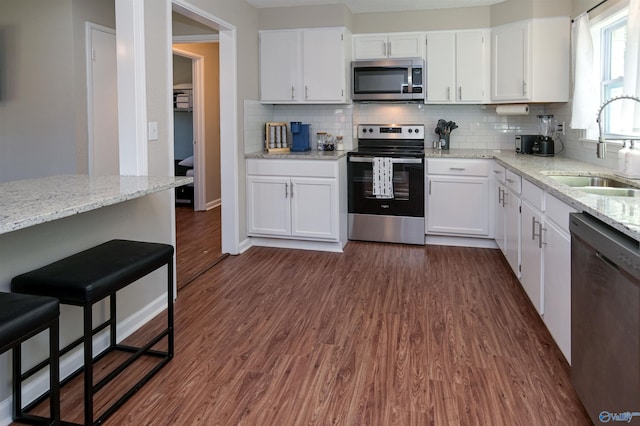 kitchen featuring white cabinets, dark wood-type flooring, stainless steel appliances, and a sink