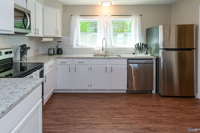 kitchen with decorative backsplash, dark wood-type flooring, stainless steel appliances, white cabinetry, and a sink