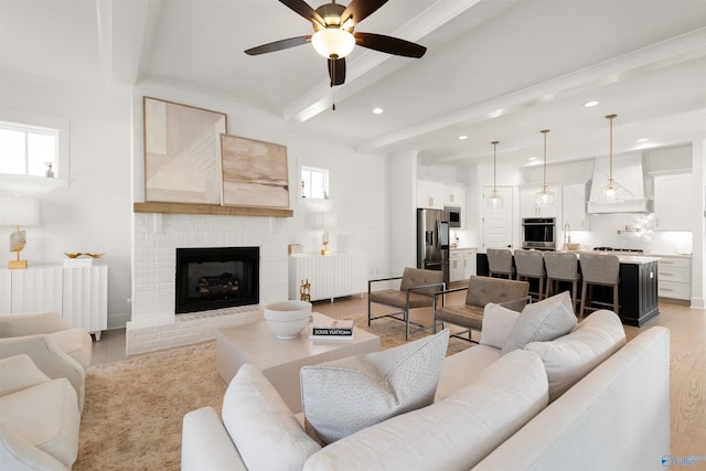 living room featuring beamed ceiling, radiator heating unit, light hardwood / wood-style floors, and a brick fireplace