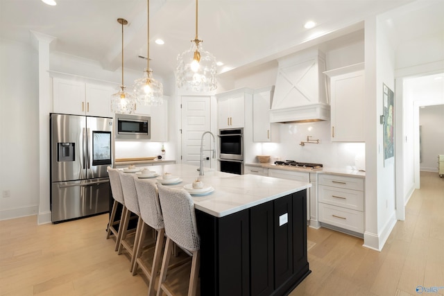 kitchen featuring stainless steel appliances, white cabinetry, premium range hood, and a center island with sink